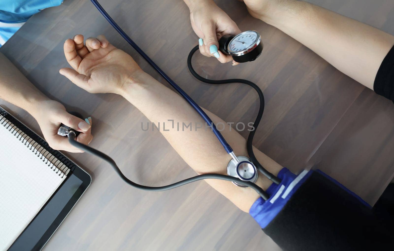 Doctor measuring blood pressure with tonometer at table in clinic closeup. Diagnosis and treatment of arterial hypertension concept