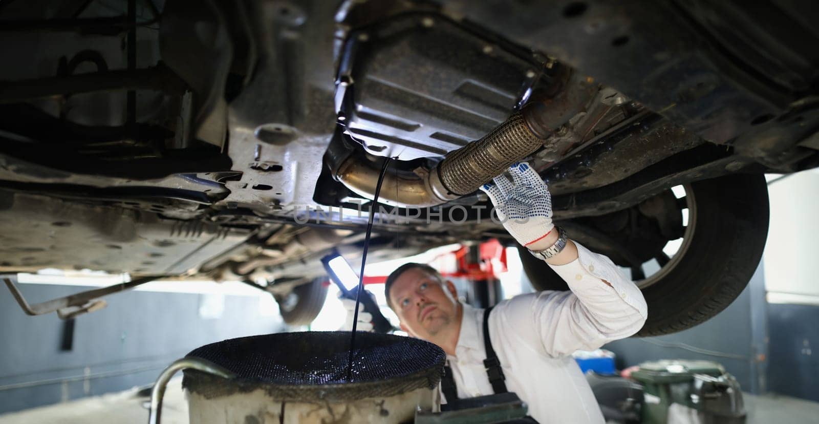 Man repairman fixing car in workshop closeup by kuprevich