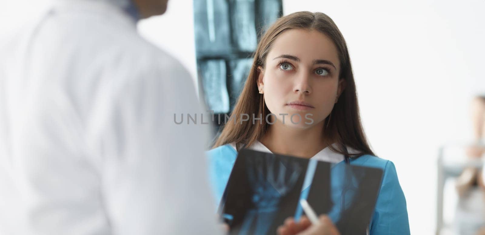 Woman doctor communicating with colleague with xrays in clinic by kuprevich