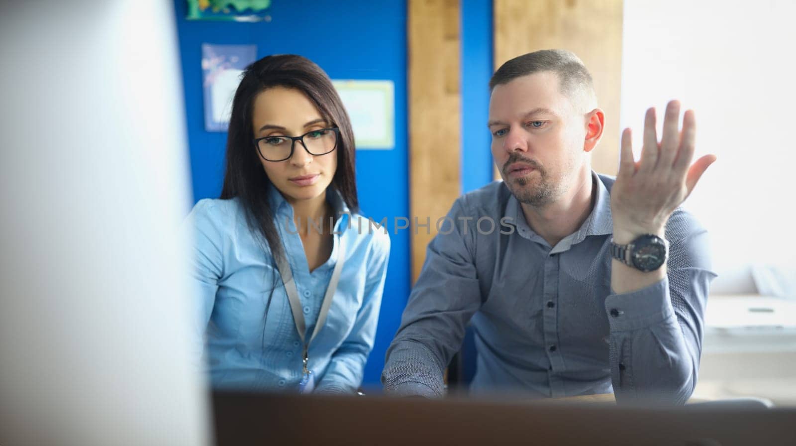 Man and woman in glasses sitting at table in front of computer screen. Business consulting concept