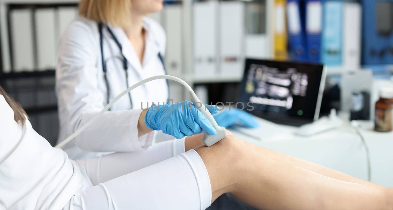 Doctor doing ultrasound examination of patient knee joint in clinic closeup. Instrumental diagnosis of rheumatic diseases concept