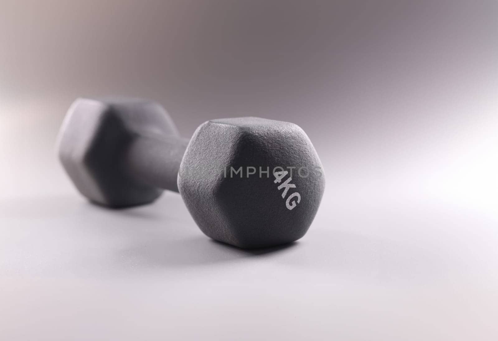 Black sports dumbbell for bodybuilding on gray background closeup by kuprevich
