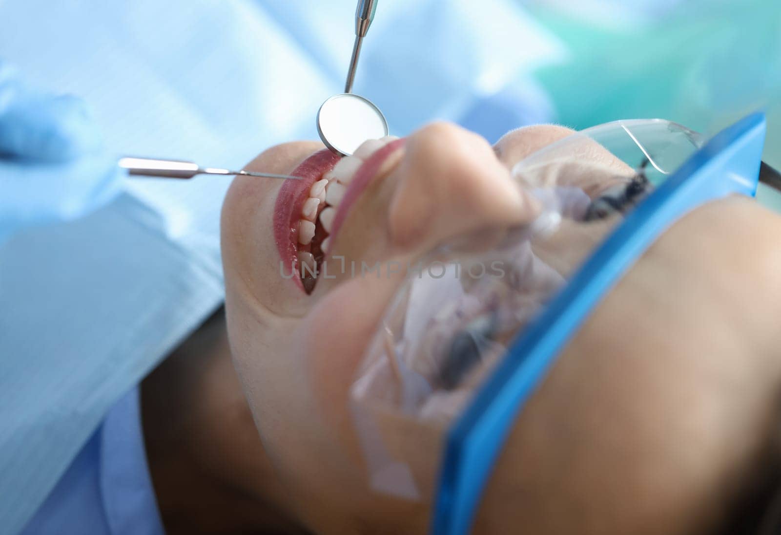 Dentist examining oral cavity of woman patient in clinic using tools closeup by kuprevich