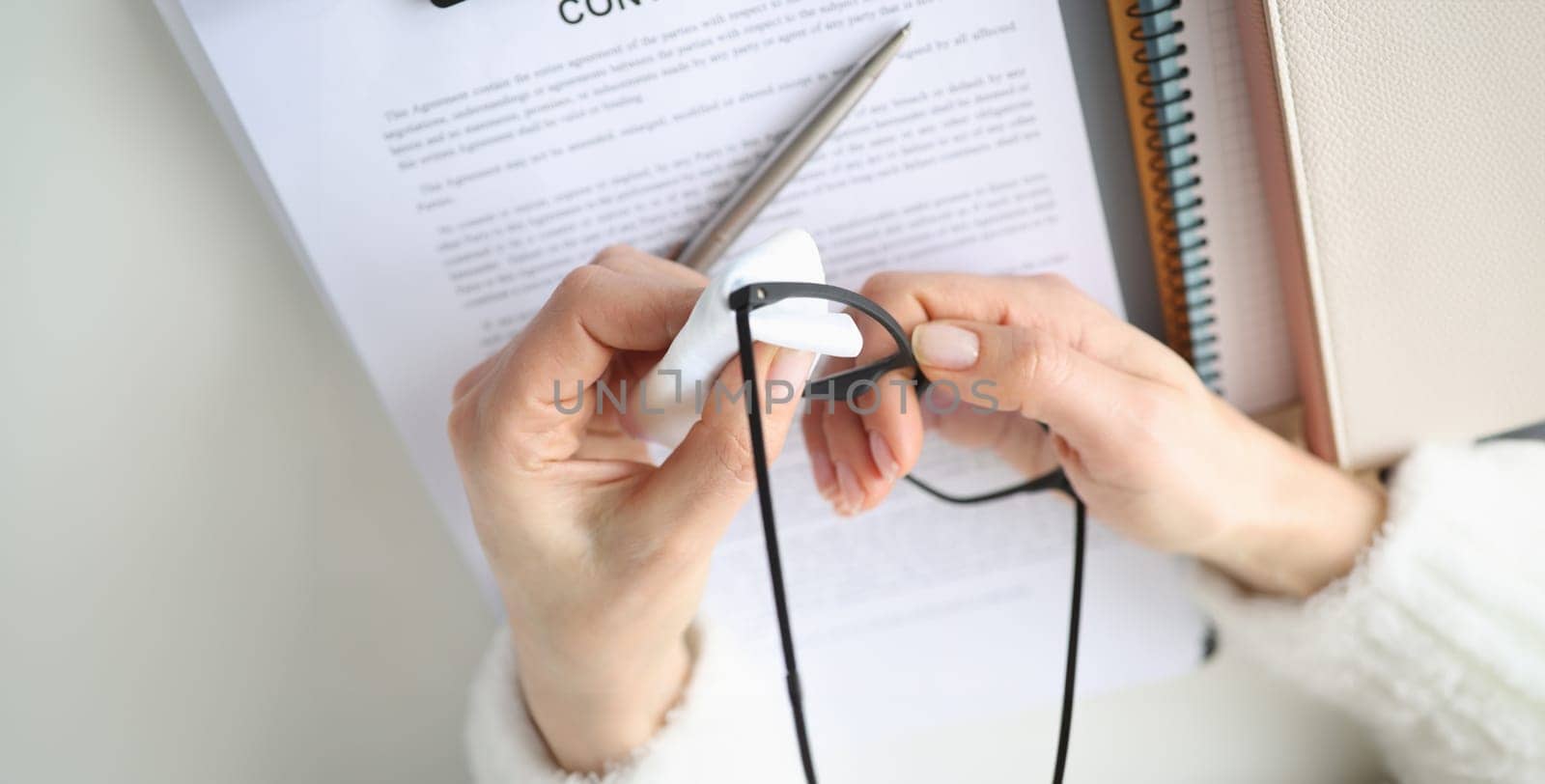 Female hands wiping eyeglasses with napkin at table closeup by kuprevich