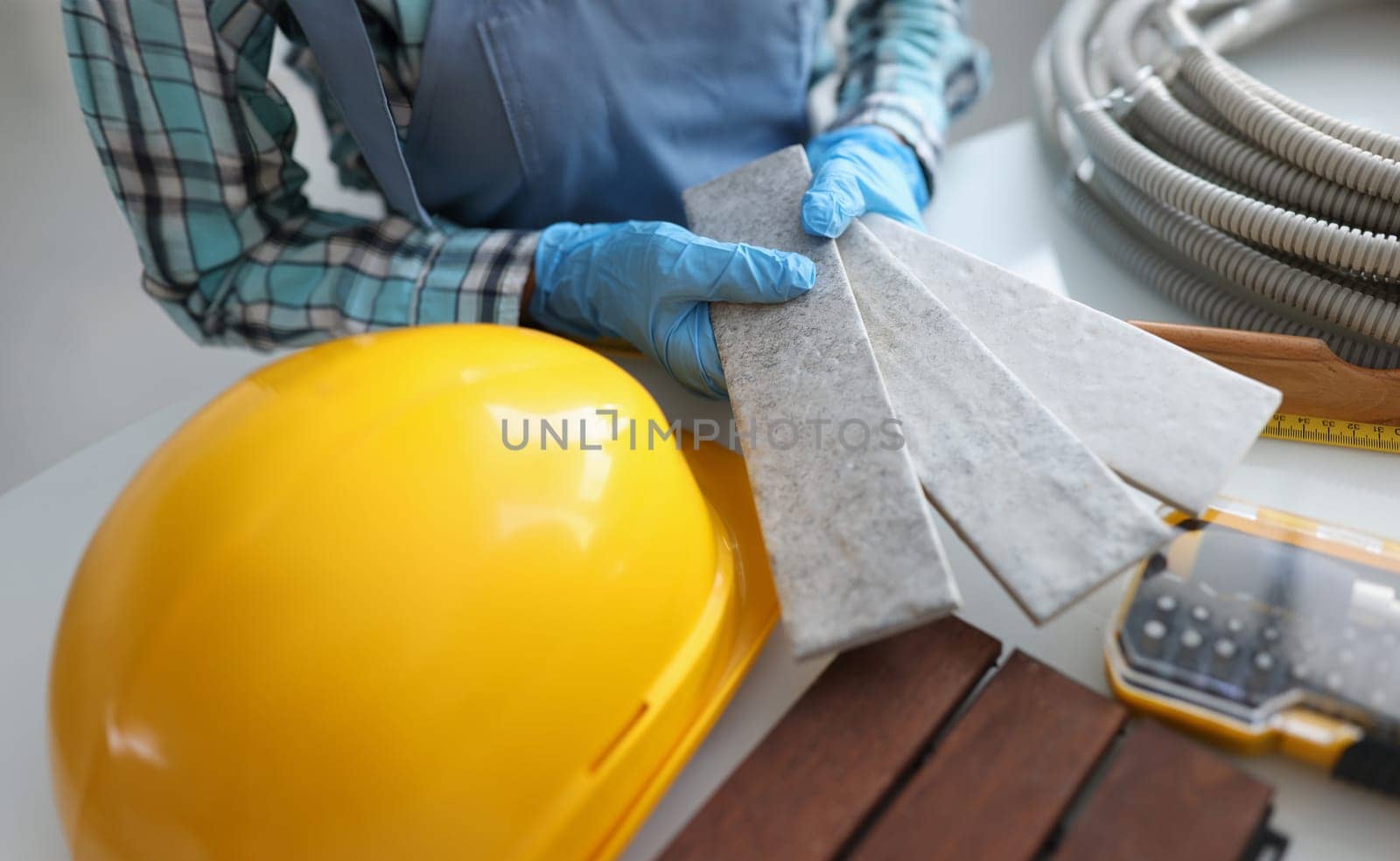 Builder holding gray tiles for bathroom in workshop closeup by kuprevich