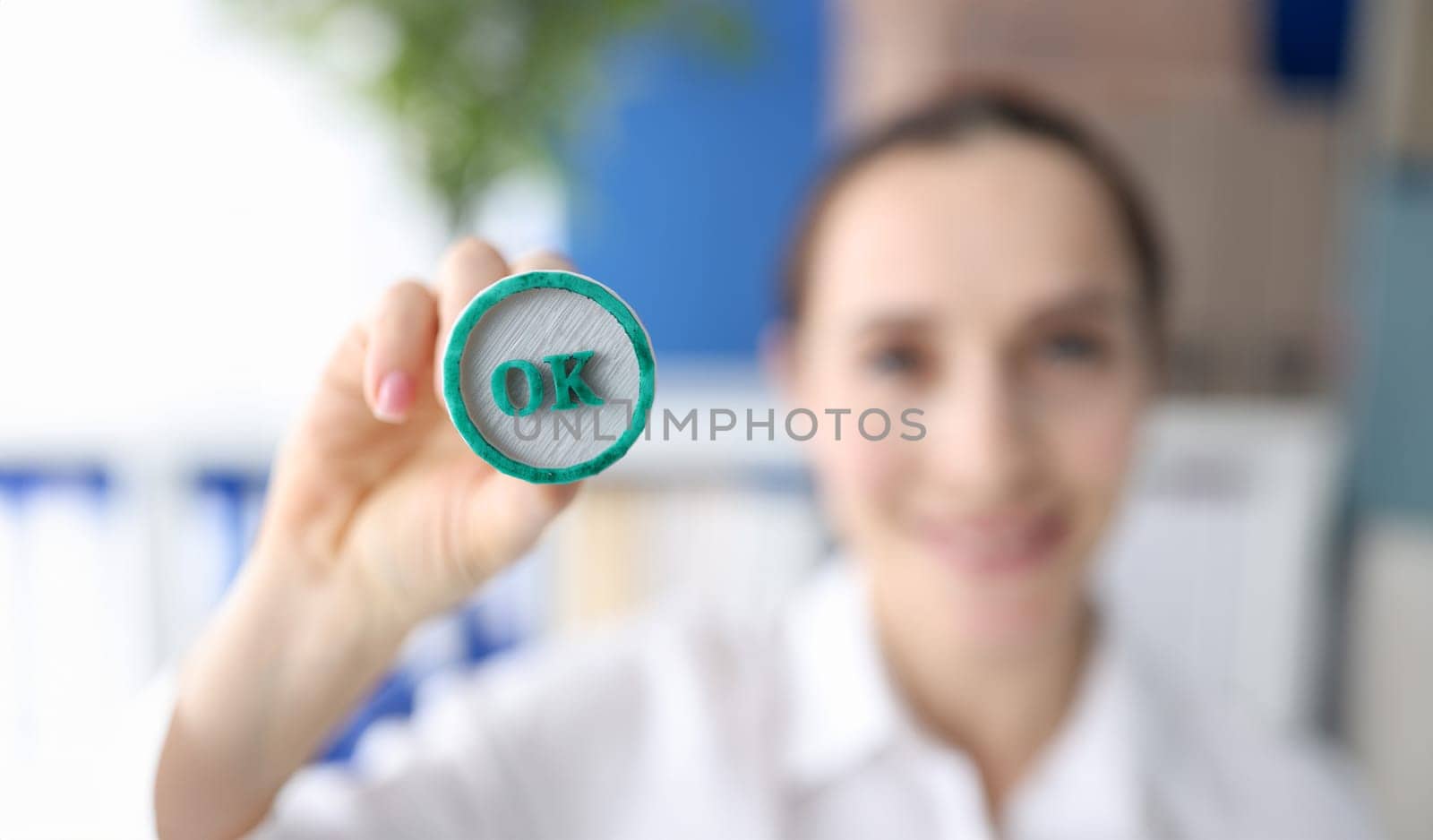 Woman holding green ink stamp OK in her hand closeup.