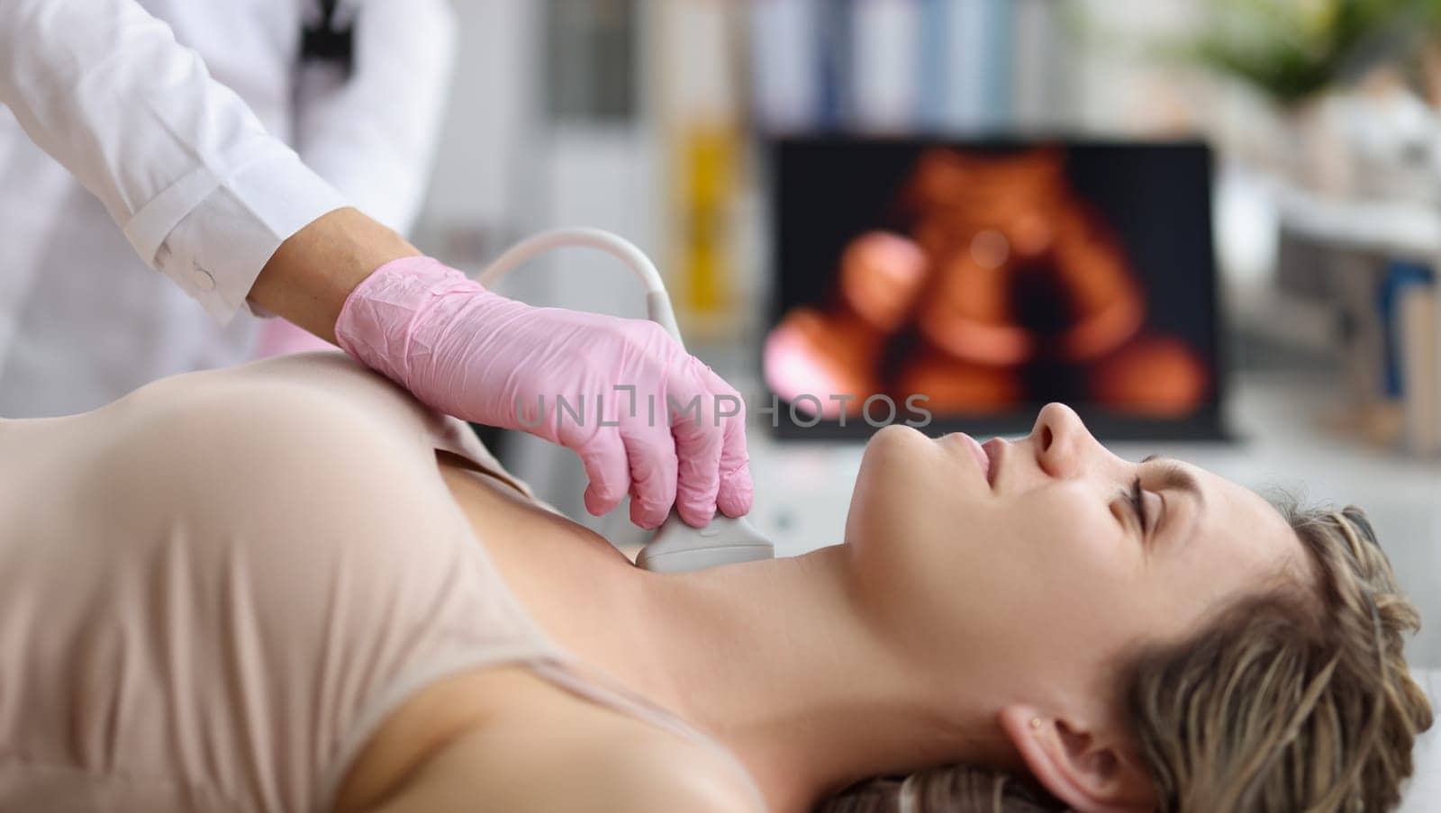 Doctor making ultrasound of thyroid gland to woman patient in clinic by kuprevich