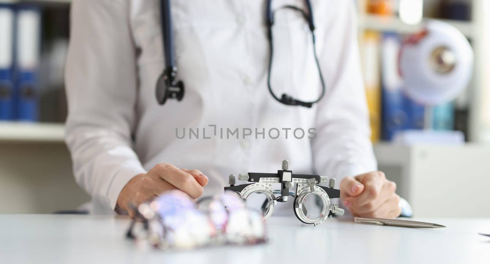 Glasses for checking vision lying on table near doctor ophthalmologist closeup. Correction of myopia selection of glasses for vision and contact lenses concept