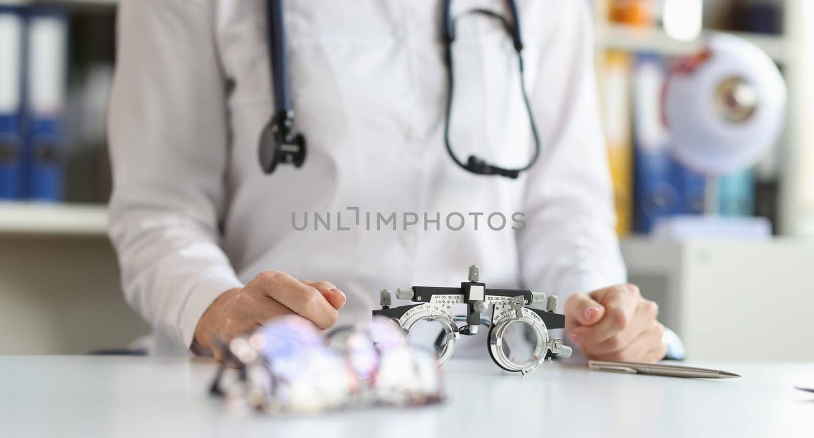 Glasses for checking vision lying on table near doctor ophthalmologist closeup by kuprevich