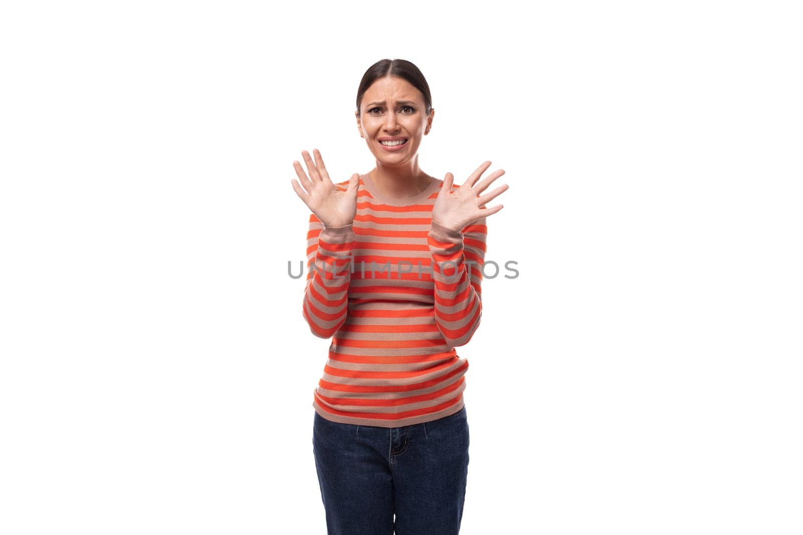 portrait of a young brunette european confused woman dressed in a casual orange sweater.