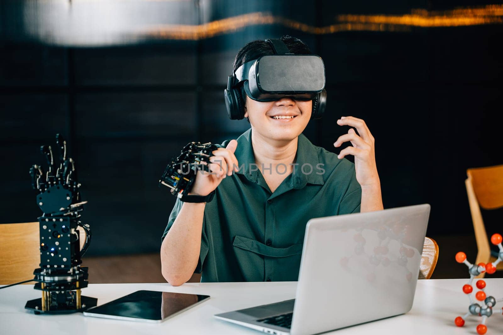 In a classroom teenager wears VR glasses while experimenting with a robot arm project. Integrating robotics programming into STEM education exploring futuristic technology. moves a robotic hand