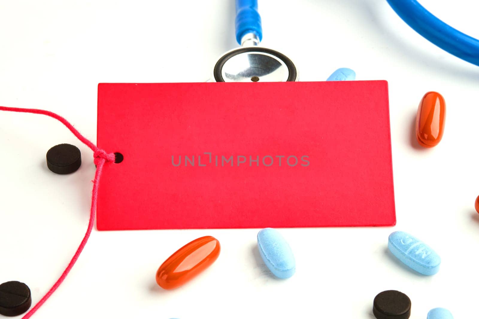 A red card on a white background. Next to the stethoscope, pills. A place to copy