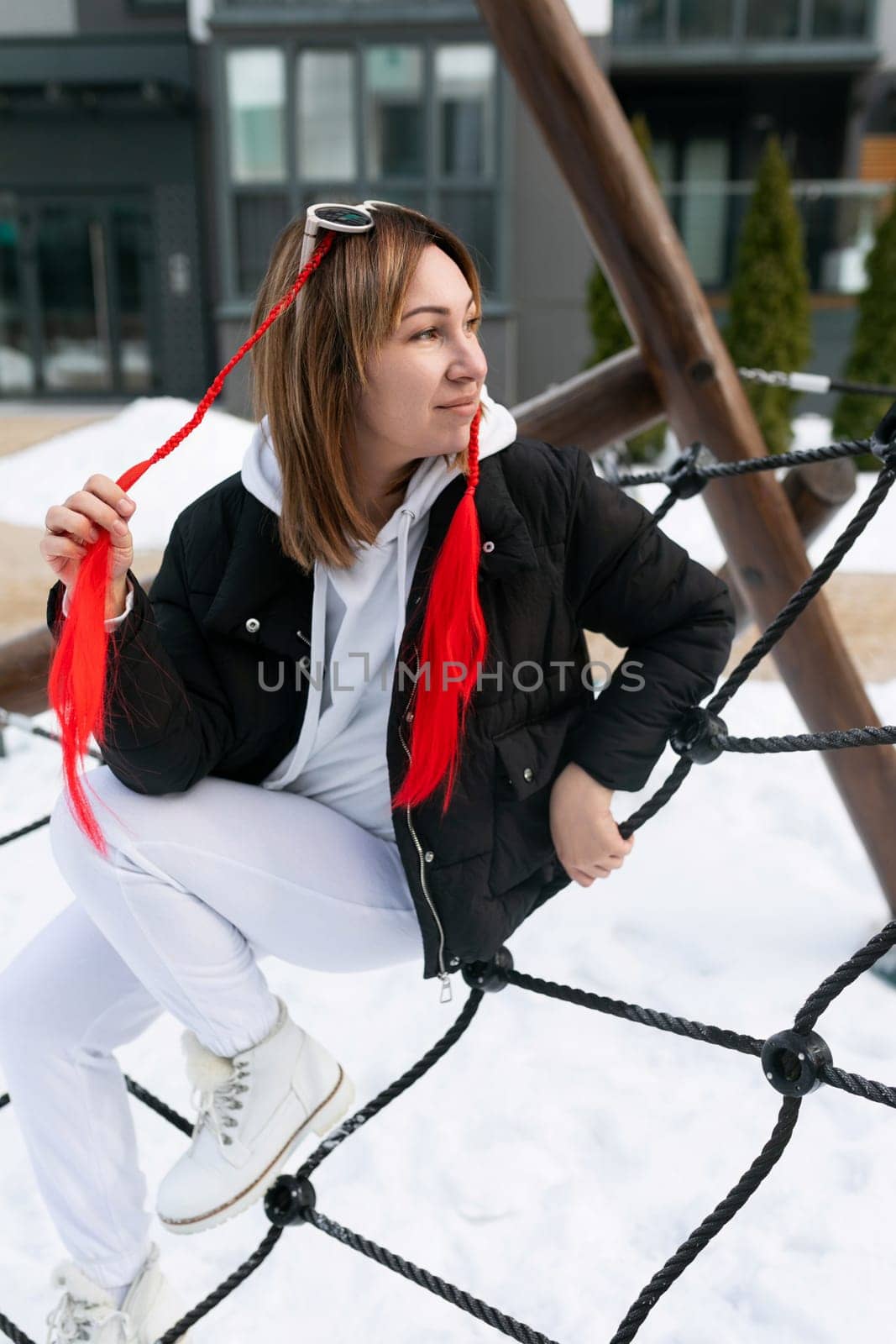 European woman in winter clothes walking on the playground by TRMK