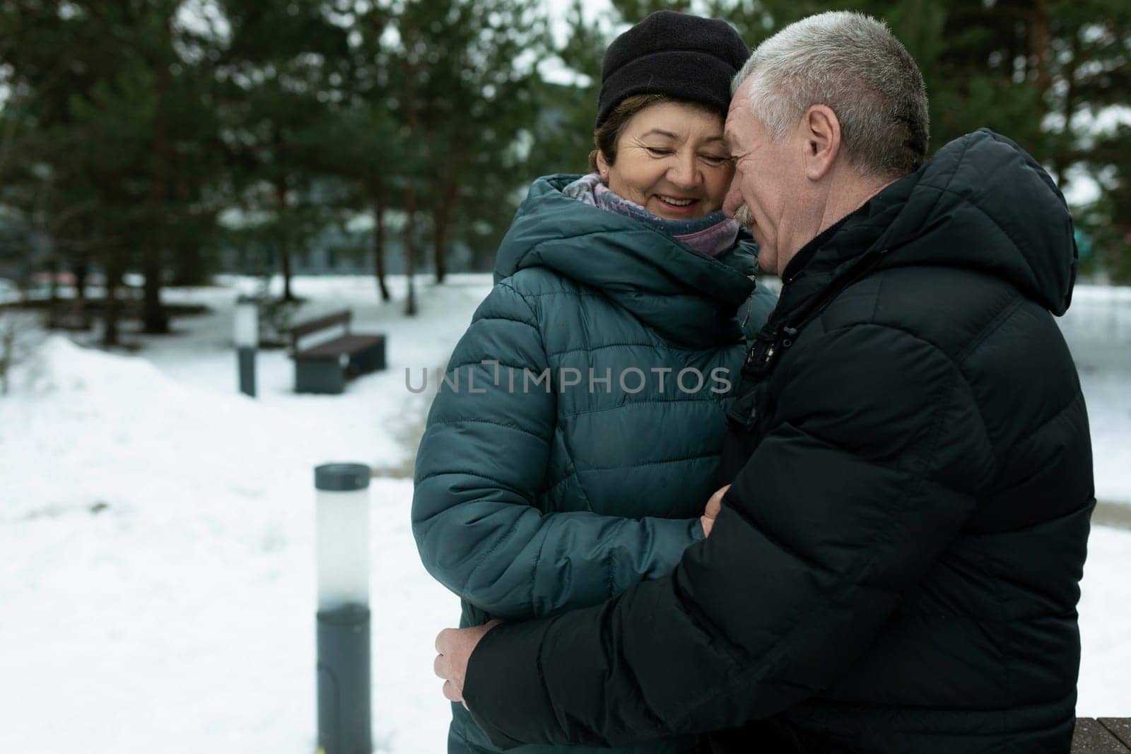 Cute mature couple experiencing love for each other while walking in the park in winter.
