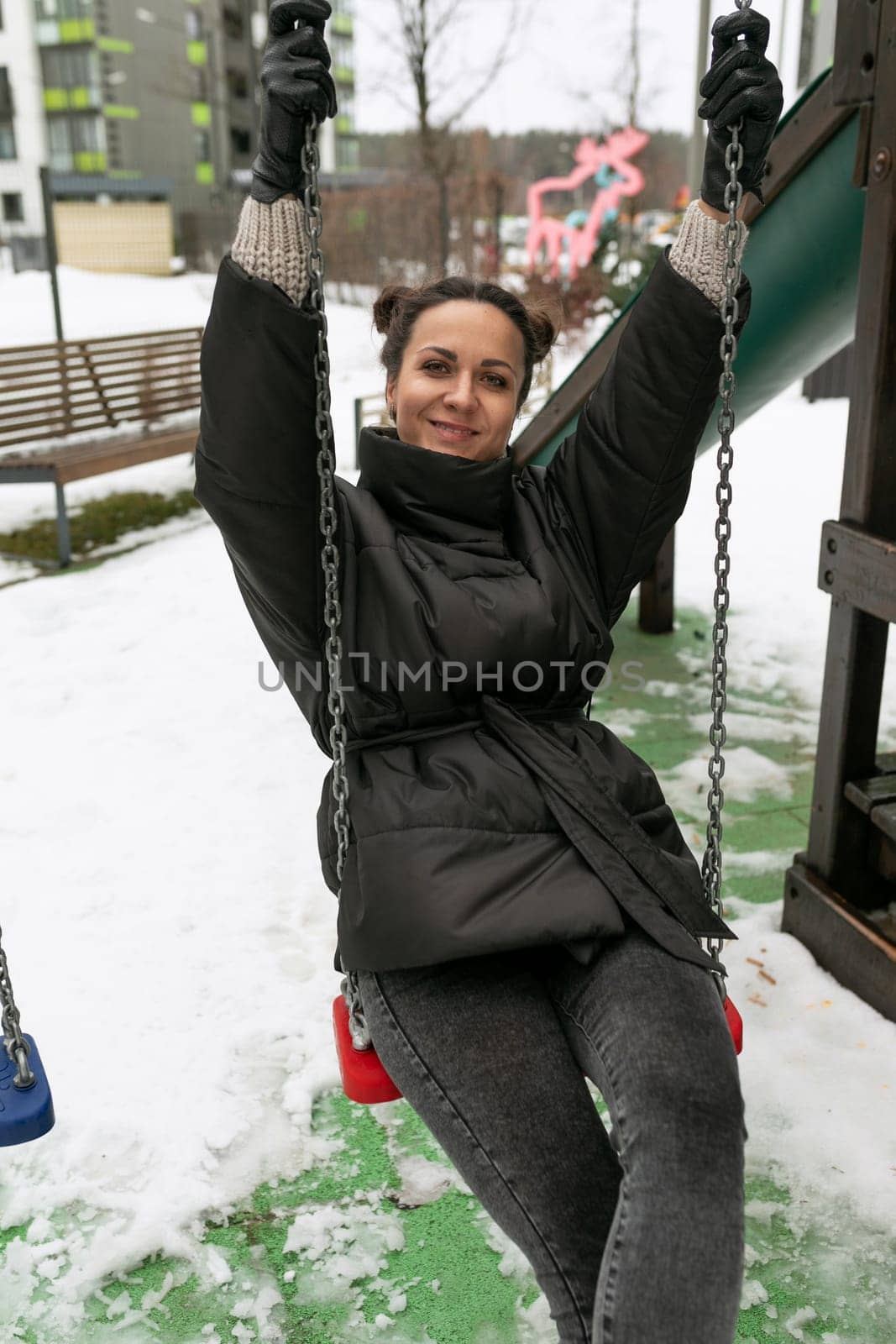 Young pretty woman in a winter jacket fooling around on the playground.