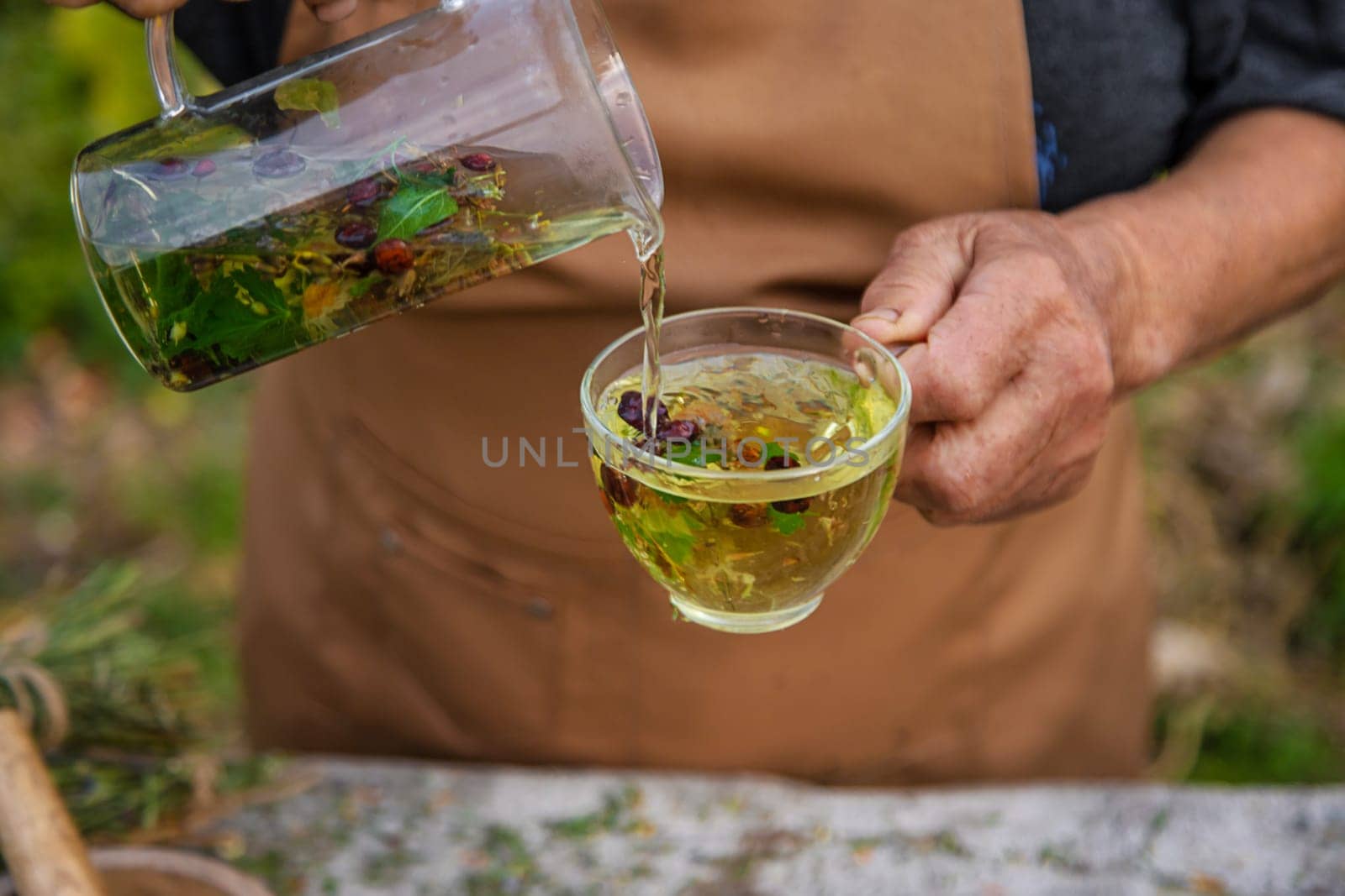 An elderly woman brews herbal tea. Selective focus. Drink.