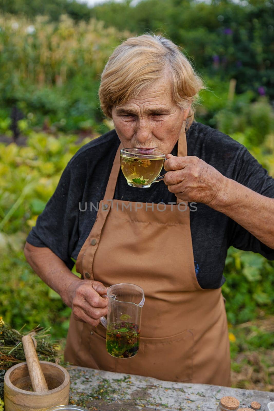 An elderly woman brews herbal tea. Selective focus. Drink.