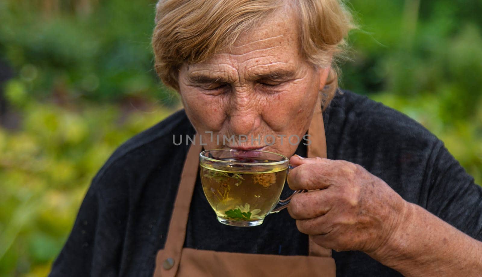 An elderly woman brews herbal tea. Selective focus. Drink.