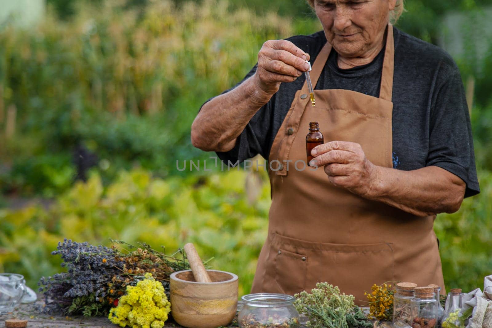 An elderly woman holds a herbal extract in her hands. Selective focus. Nature.