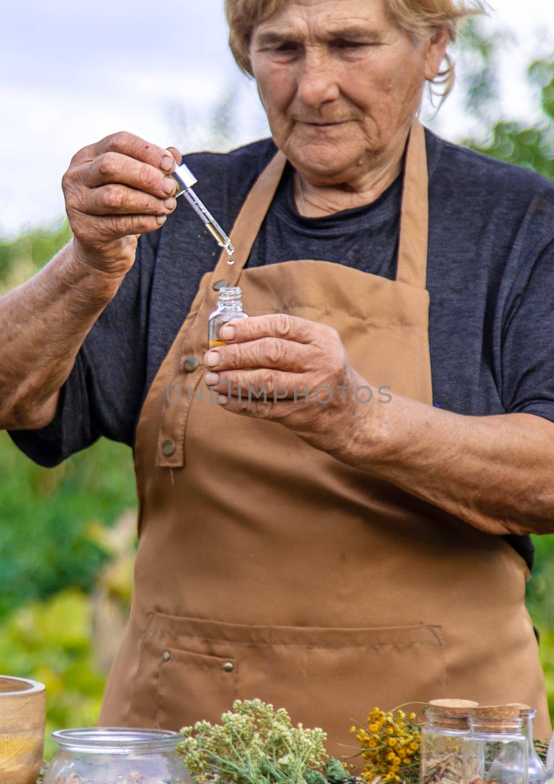 An elderly woman holds a herbal extract in her hands. Selective focus. Nature.