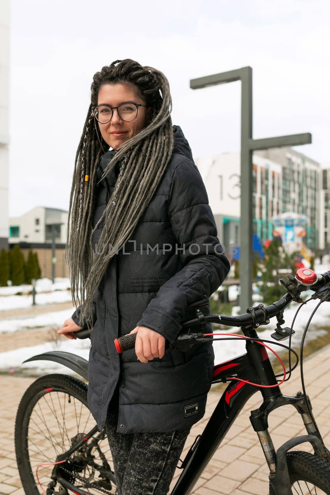 A pretty young woman with a dreadlocked hairstyle rides a rented bicycle by TRMK