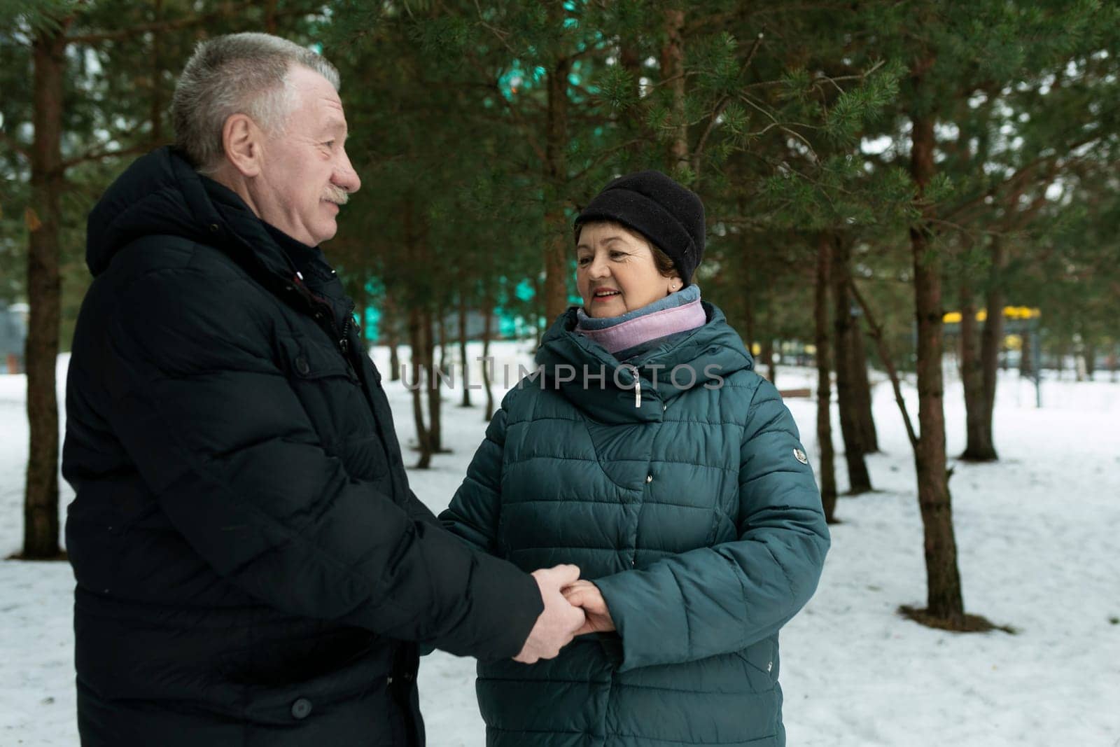 Happy elderly couple feels tenderness for each other while walking in the park by TRMK