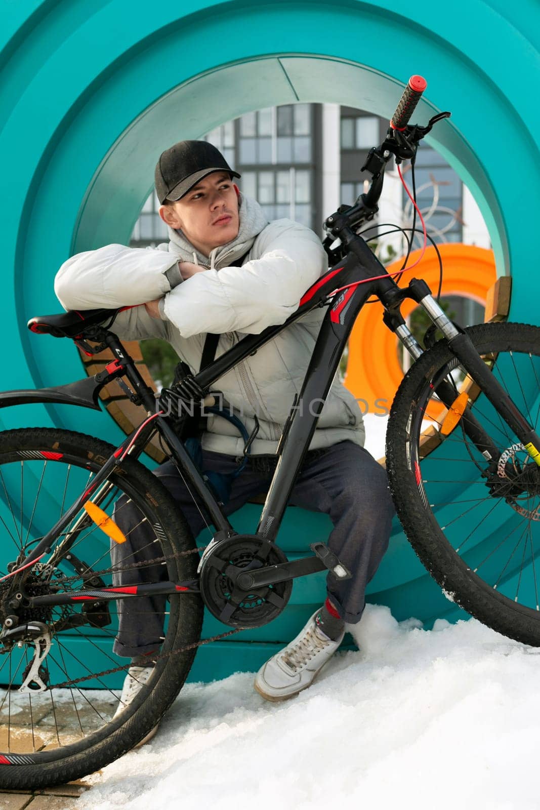 A young man in autumn clothes sat down to rest after a bike ride.