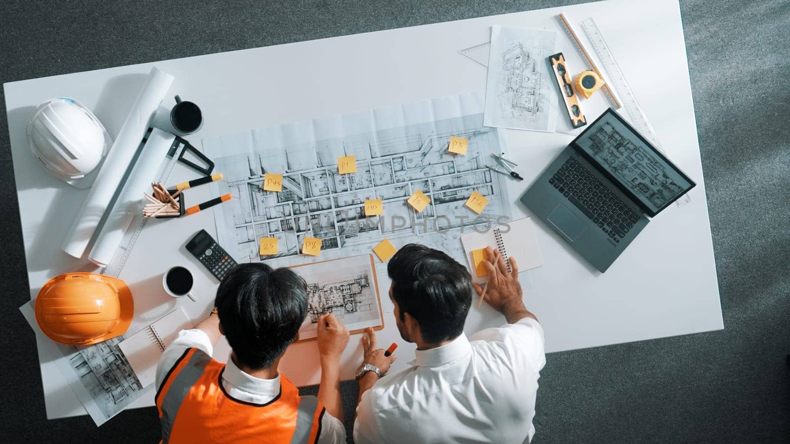 Top down aerial view of smart architect engineer team pointing and discussing about building construction. Group of diverse people working together to plan and design by using blueprint. Alimentation.