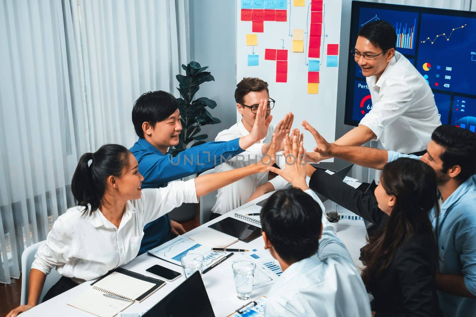 Analyst team leader celebrate and high five together with his colleague after successful data analysis meeting using FIntech software power with business intelligence or BI dashboard. Prudent