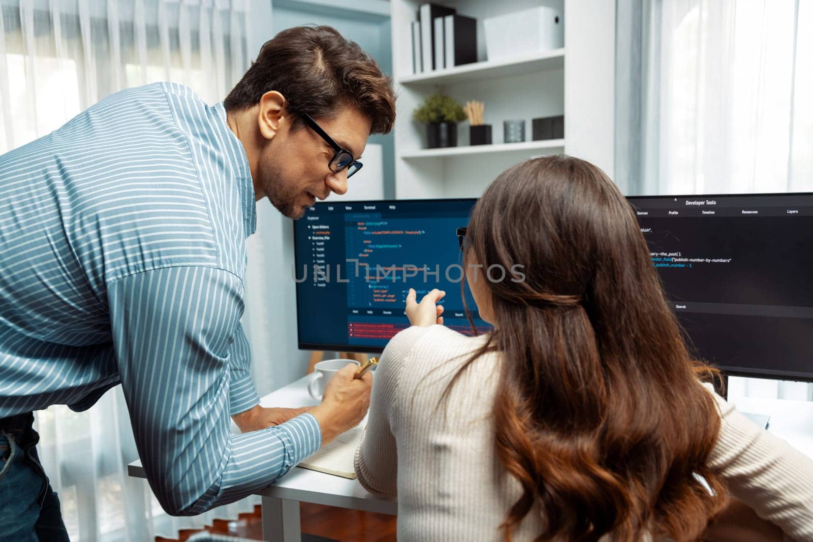 Team skilled developers program coding discussing creative website planning software project on two screen monitor's full stack data analyzing design at office with back side view concept. Postulate.