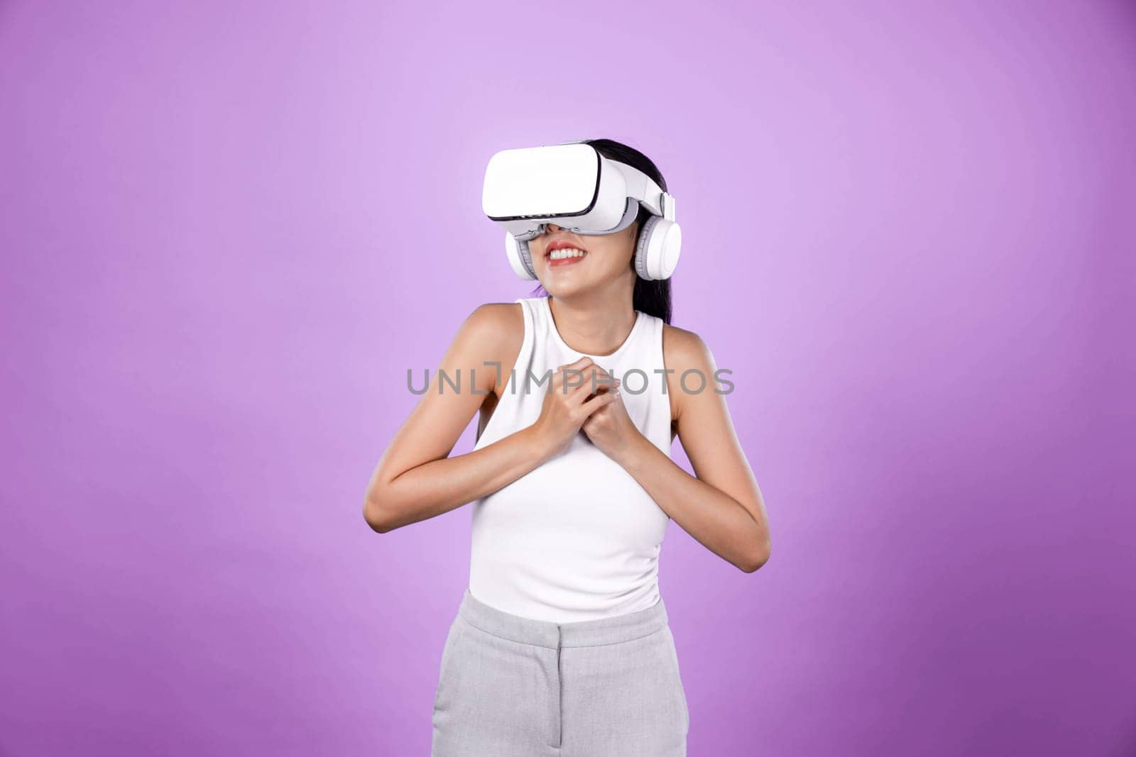 Smart female standing with pink background wearing VR headset connecting metaverse, futuristic cyberspace community technology. Elegant woman excited seeing generated virtual scenery. Hallucination.