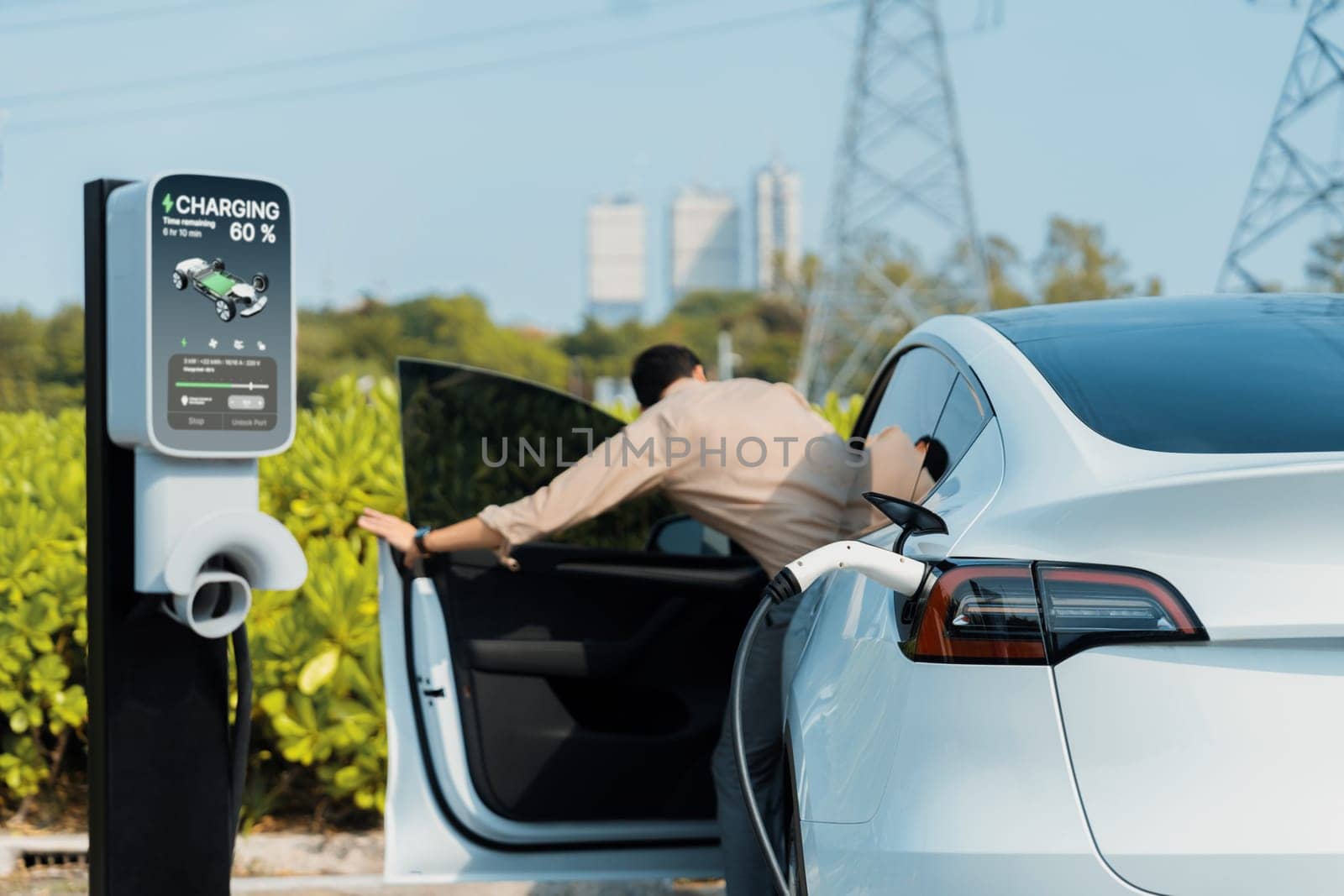 Young man recharge EV car battery at charging station. Expedient by biancoblue