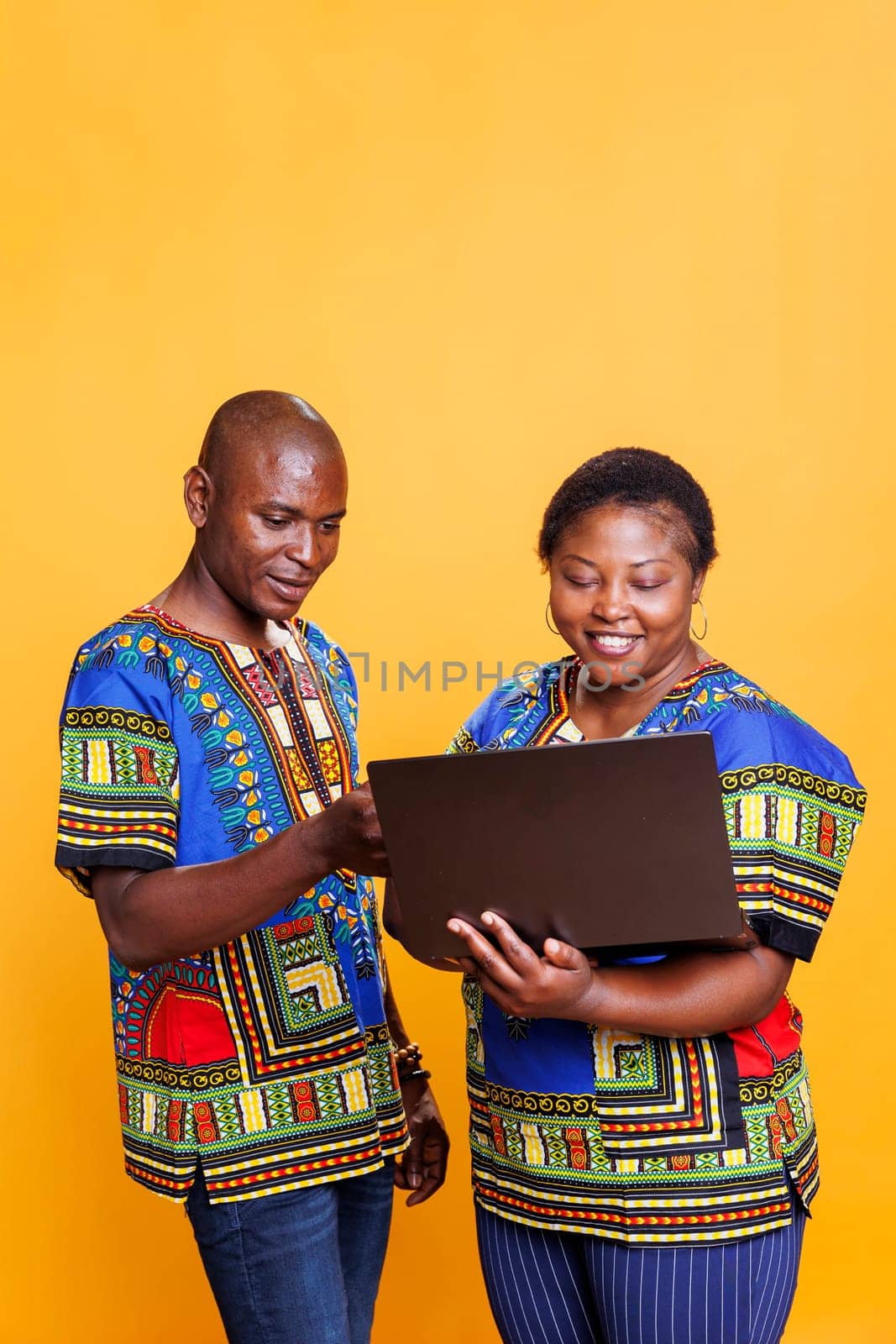 African american couple standing with laptop and choosing product in online store. Cheerful man and woman paying on internet while shopping together using portable computer