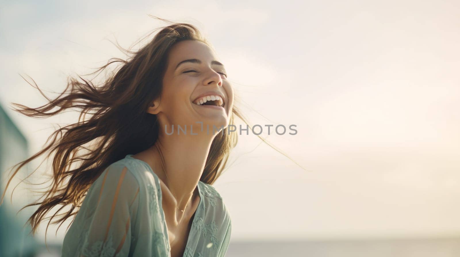 A happy young woman is captured in a moment of laughter, with her hair blowing in the sea breeze during a beautiful sunset - Generative AI