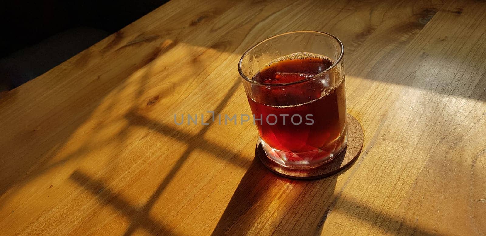 Transparent Glasses with sweet drinks inside with colorful drink, with shadow and table background with ice cubes on a bar restaurant