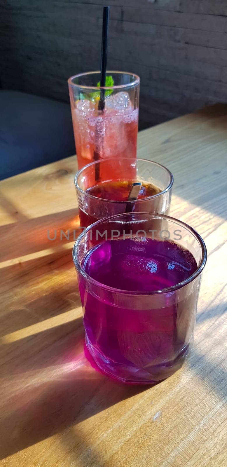 Transparent Glasses with sweet drinks inside with colorful drink, with shadow and table background with ice cubes by antoksena