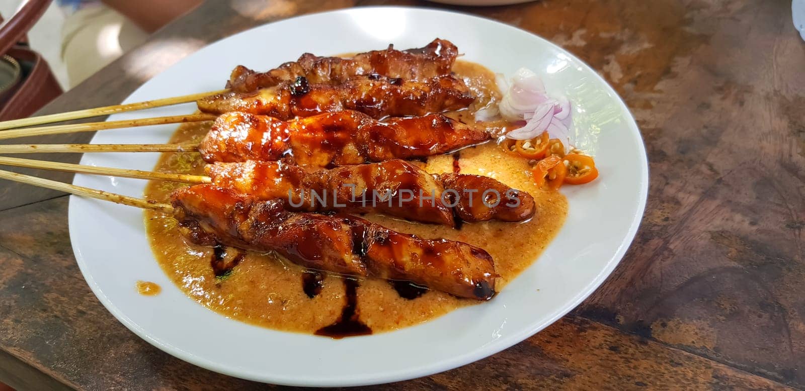 Chicken satay or Indonesian sate ayam, grilled chicken satay with peanut and soy sauce completed with chili and onion, indonesian delicacy