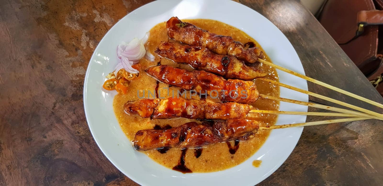 Chicken satay or Indonesian sate ayam, grilled chicken satay with peanut and soy sauce completed with chili and onion, indonesian delicacy