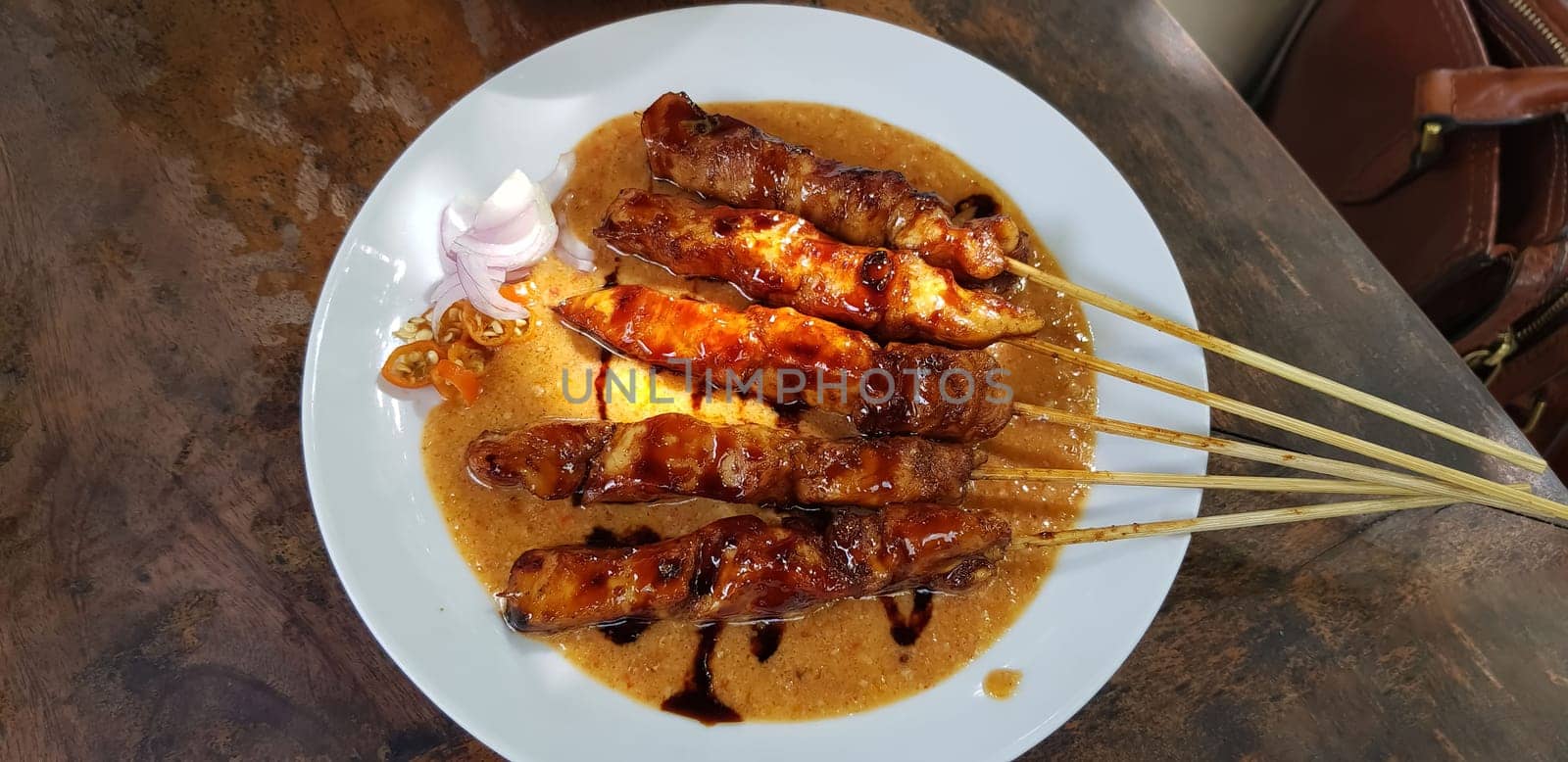 Chicken satay or Indonesian sate ayam, grilled chicken satay with peanut and soy sauce completed with chili and onion, indonesian delicacy