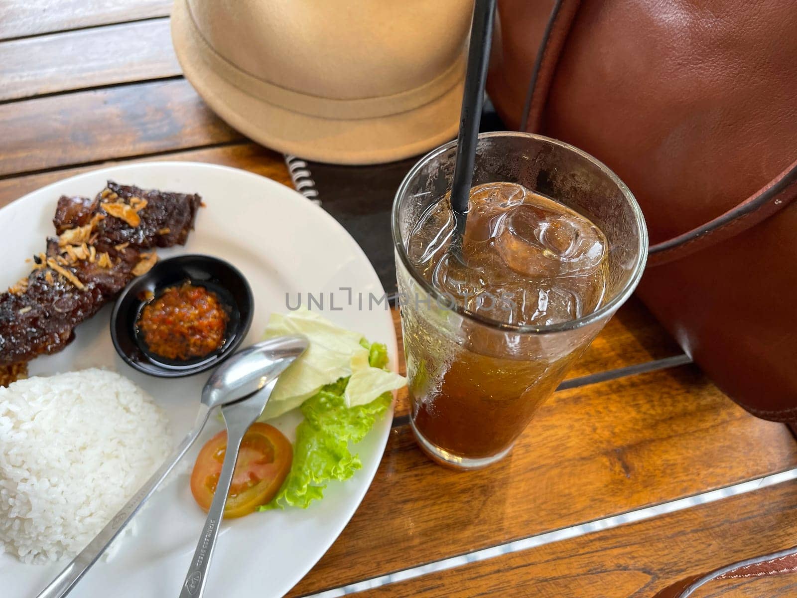 Spicy hot grilled honey roasted spare ribs from summer BBQ served with hot chili paste and rice also ice tea served in white plate