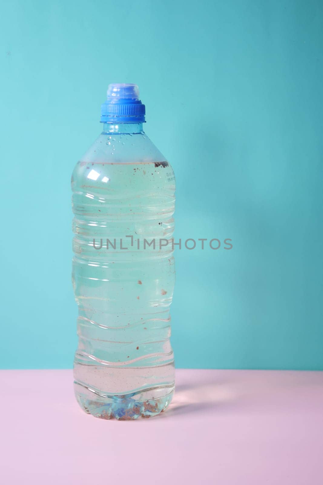 dirty bottle of water on table by towfiq007