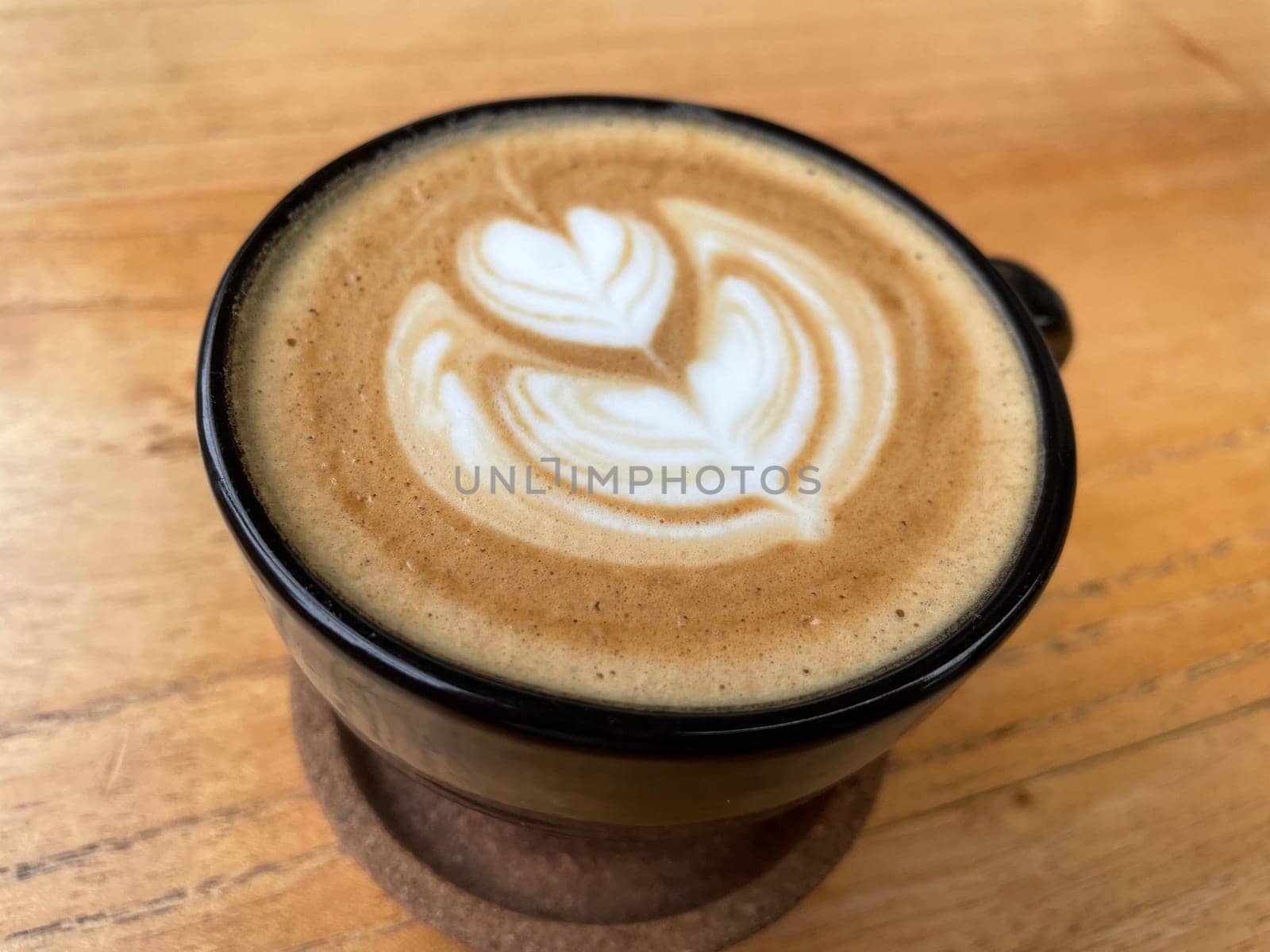 beautiful cup of cappuccino coffee with latte art in the wooden space background