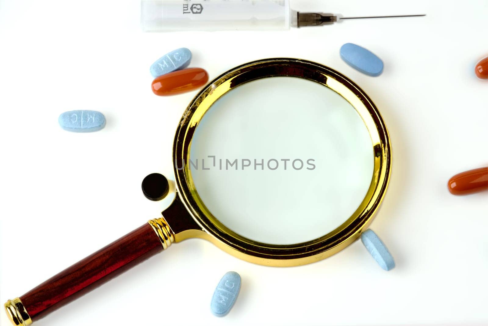 A magnifying glass next to the pills on a white background. A conceptual photo. A place to copy. Treatment concept