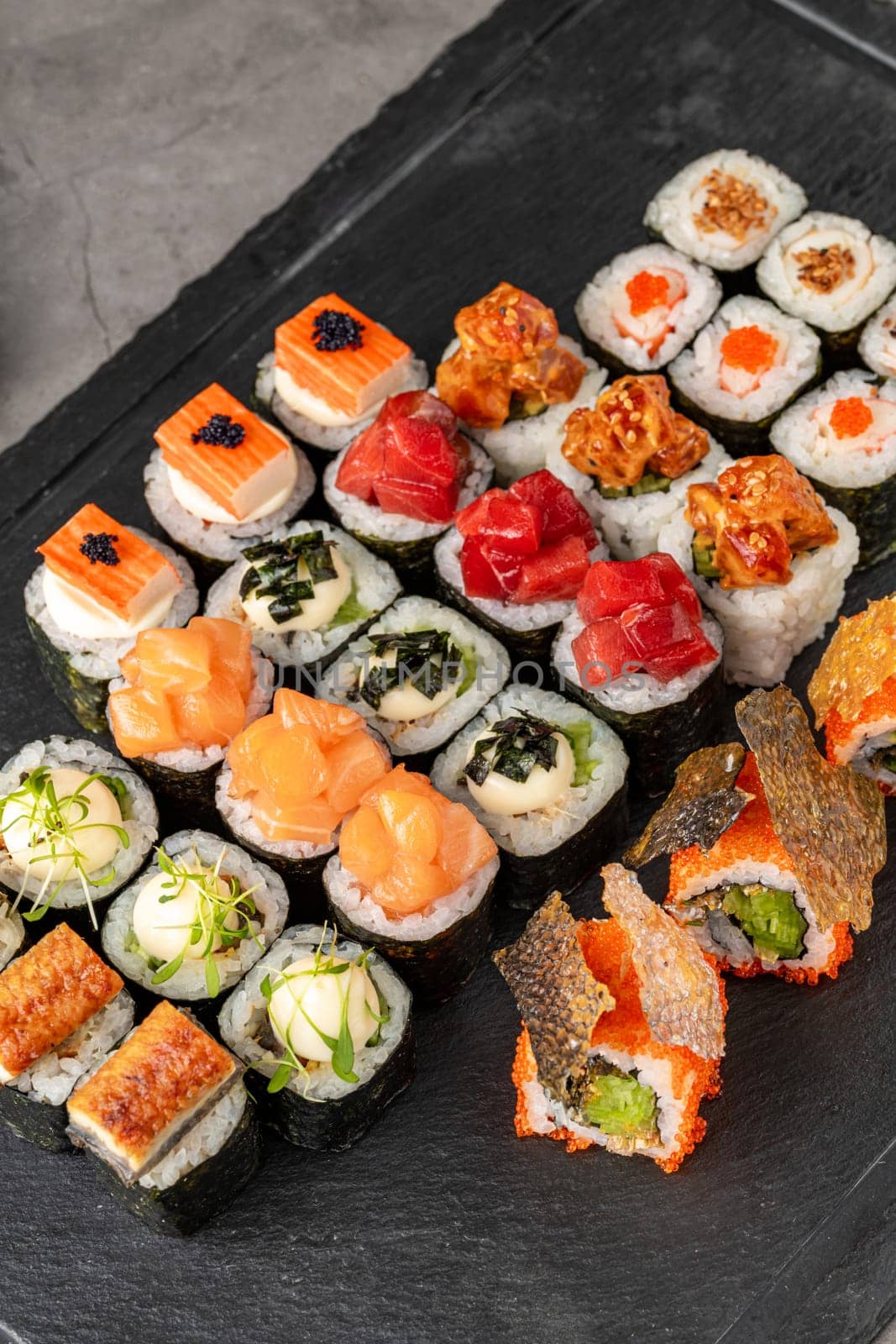 Sushi set of various products on a black stone plate