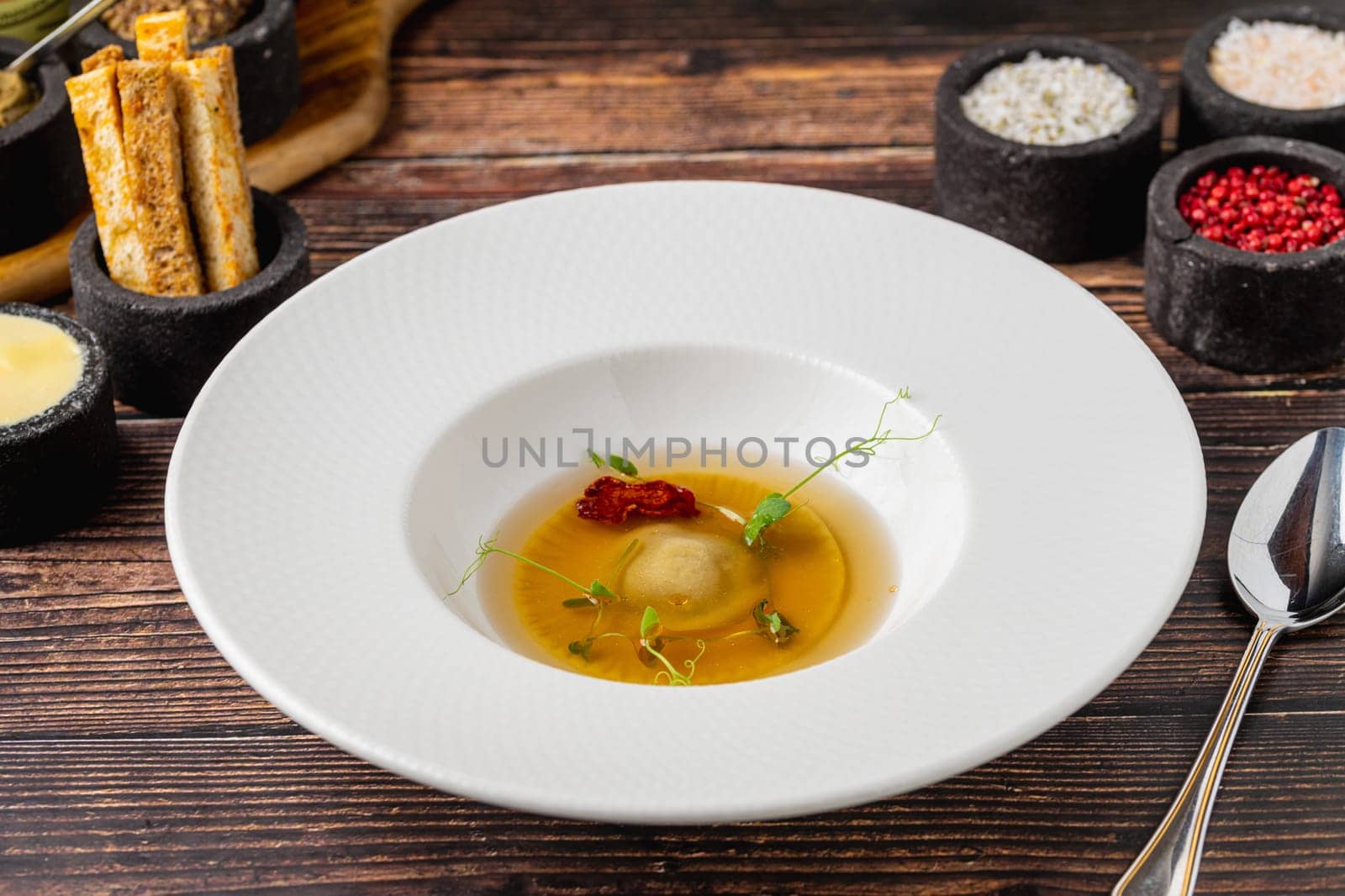 Ravioli consomme on a white porcelain plate. Healthy eating concept by Sonat