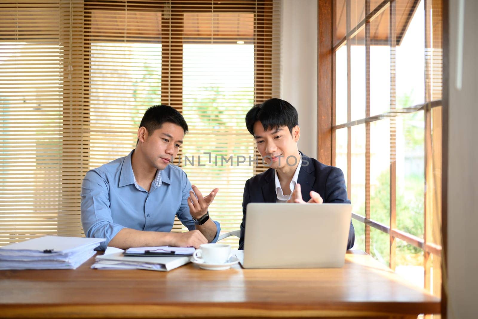 Portrait of smart businessmen discussing financial market data on laptop in their office by prathanchorruangsak