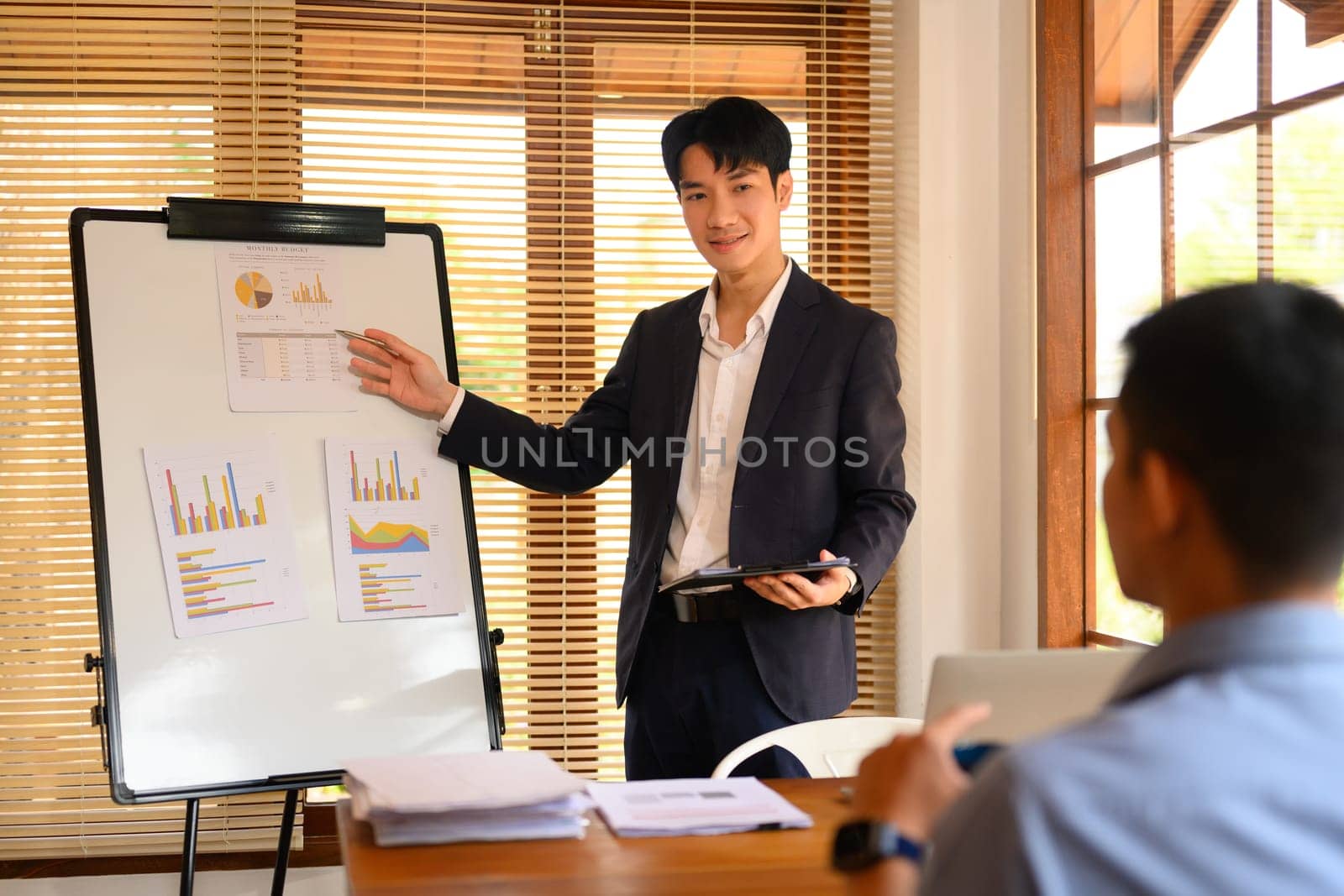 Shot of confident male employee presenting analysis of financial data on a whiteboard at meeting.