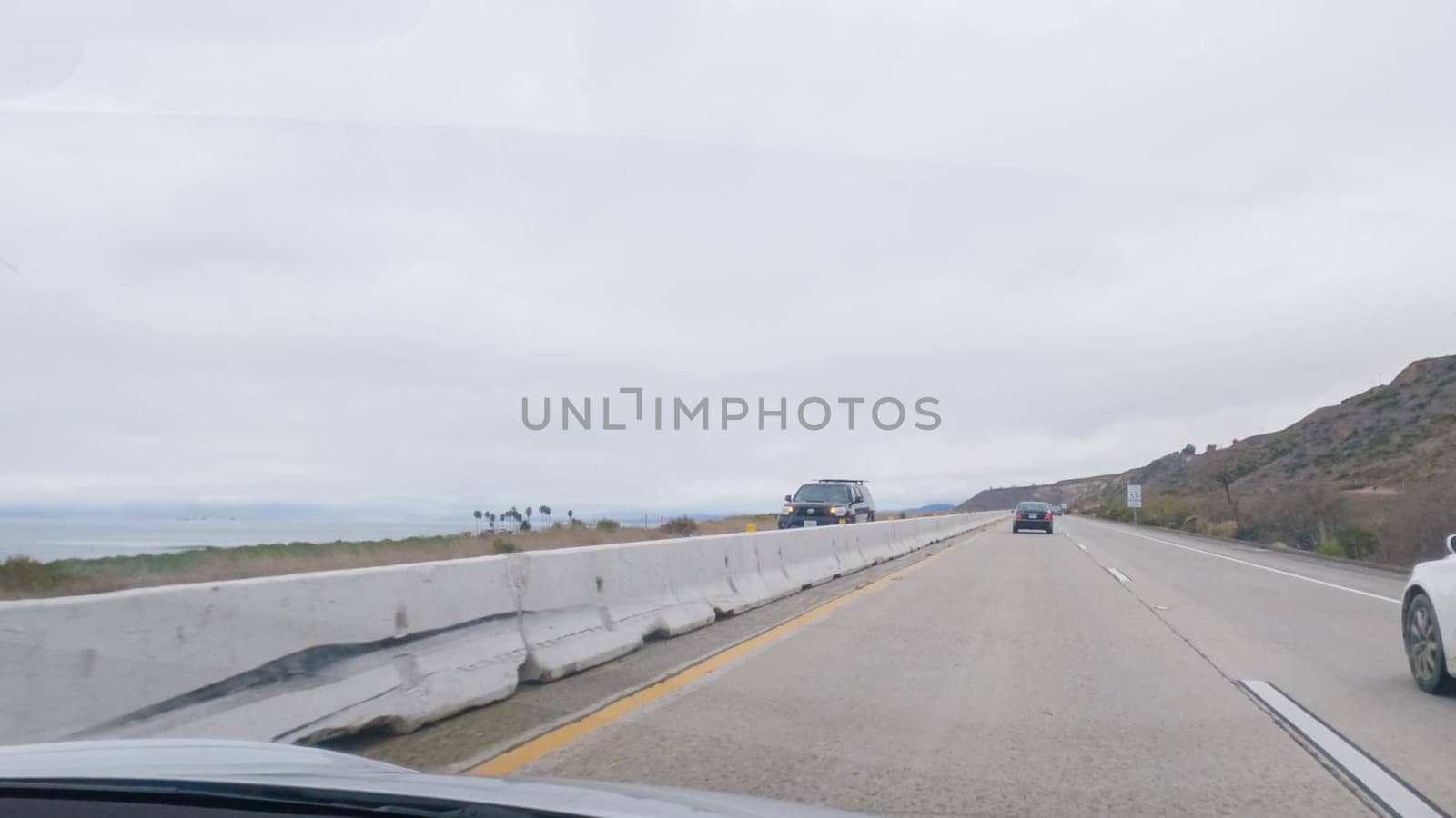 Driving along Highway 101 near Rincon Beach, California, amidst a gloomy, cloudy winter day.