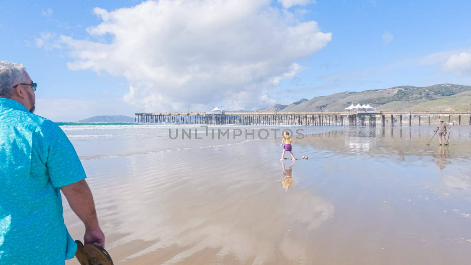 Father and daughter enjoy a leisurely winter walk along the picturesque Pismo Beach, sharing quality time together amid the serene backdrop of gently crashing waves.