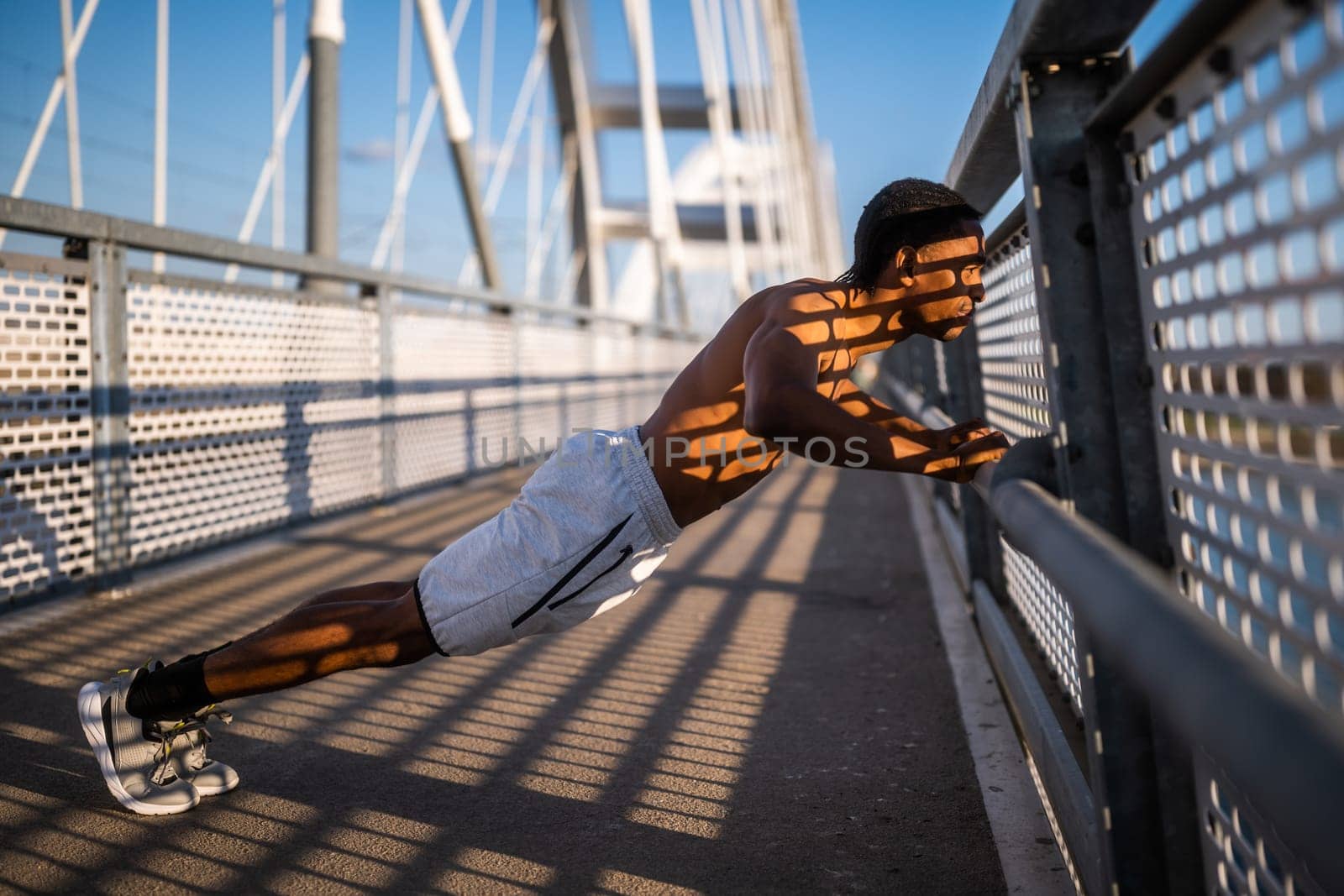Young  man is exercising on the bridge in the city. He is doing push-ups.